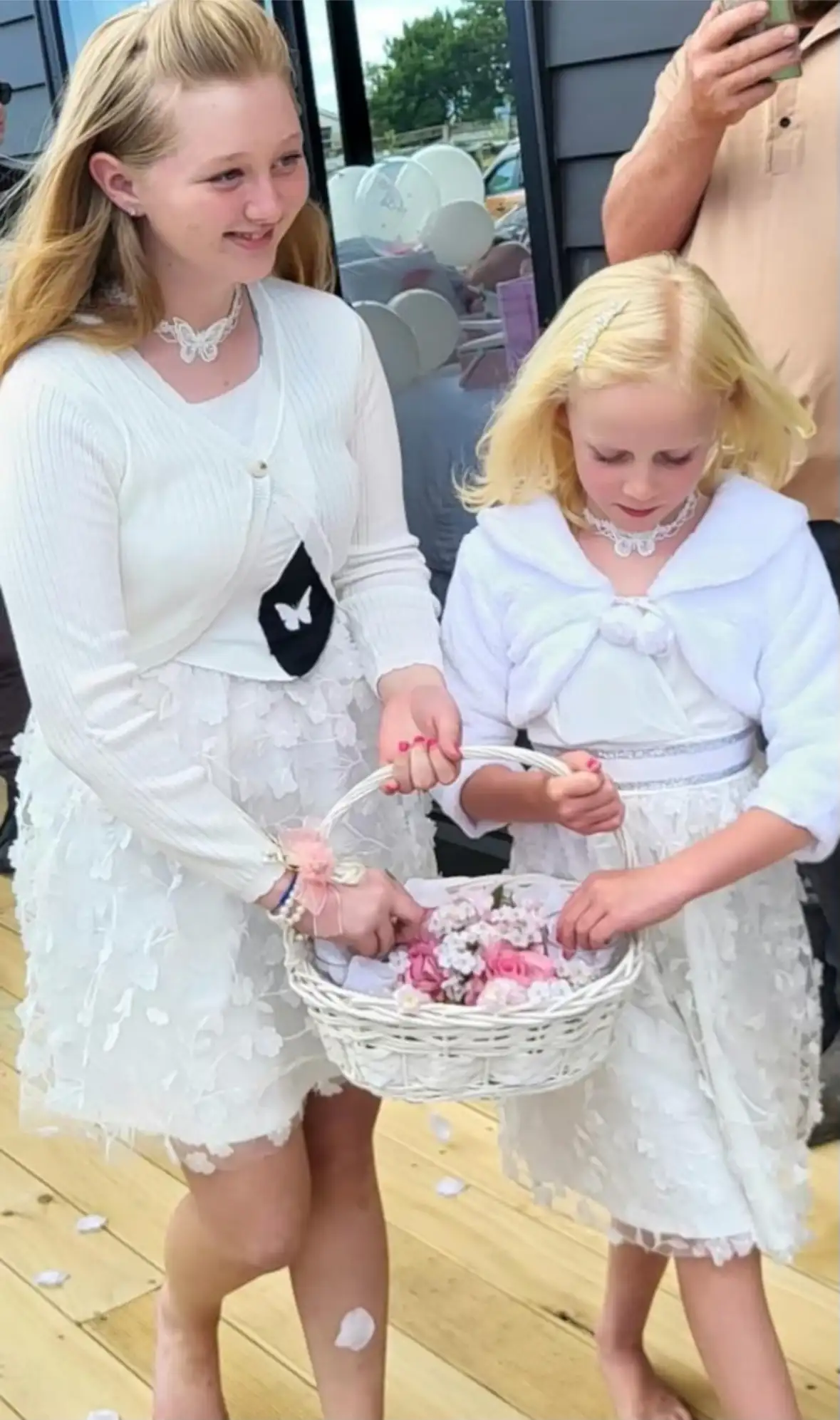 Two flower girls carrying a basket of petals at a vow renewal